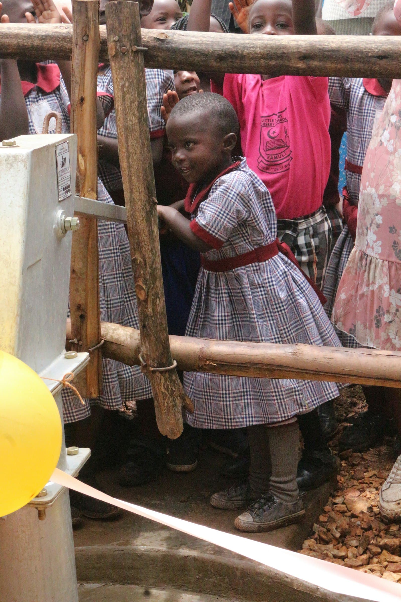 Happy children smiling around a community water pump